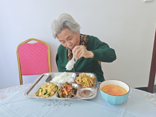 陈中娥老人端着搭配得当的三菜一汤，心满意足地坐下享用